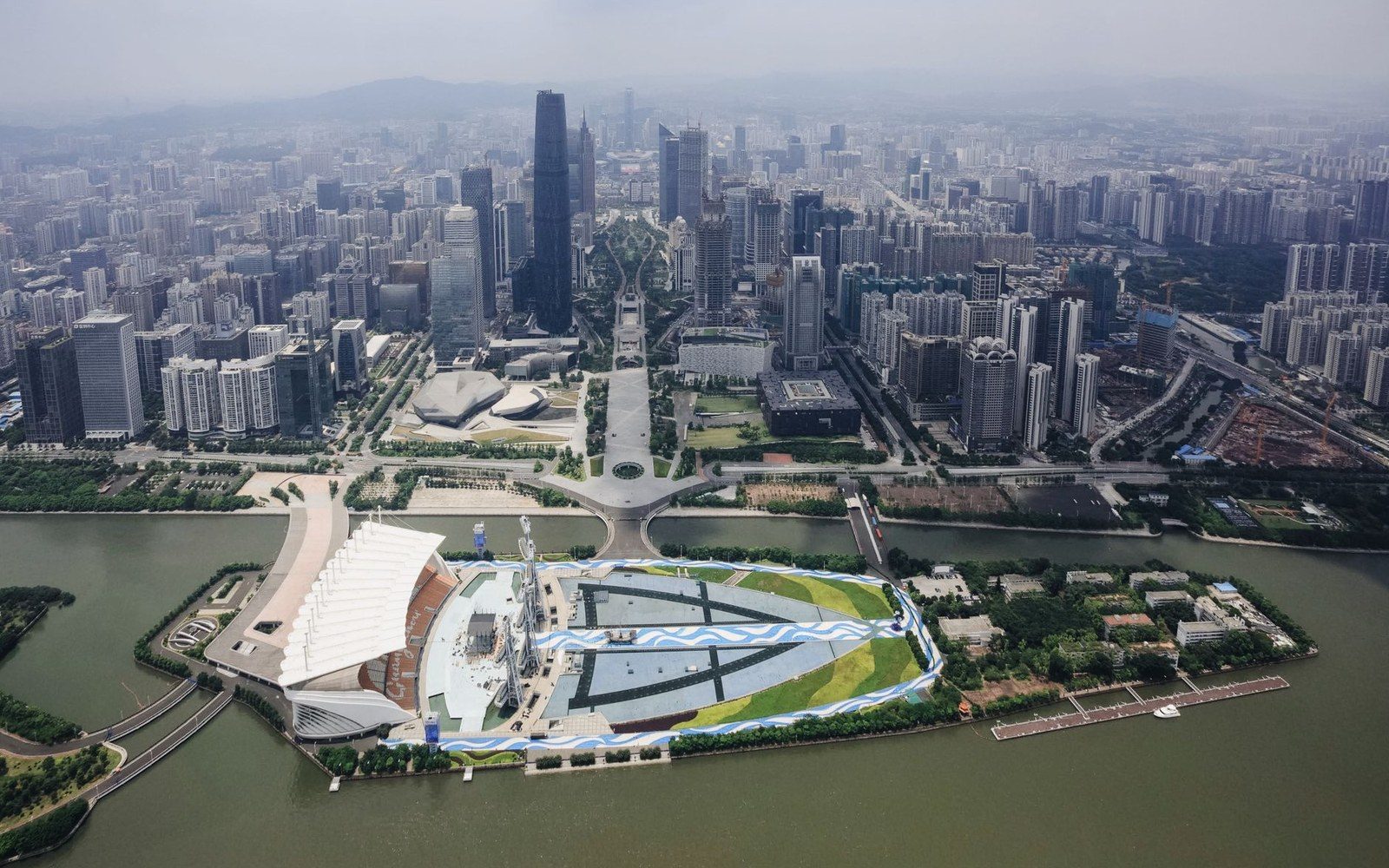Aerial view of a dense city skyline along a river with a distinctive waterfront museum building